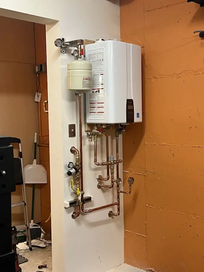 Plumbing technician inspecting water heater connections in East Wenatchee